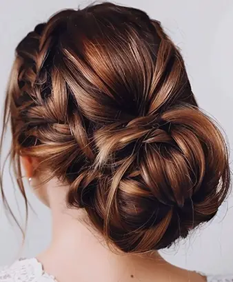 Low Plaited Brunette Bun With Wavy Tendrils